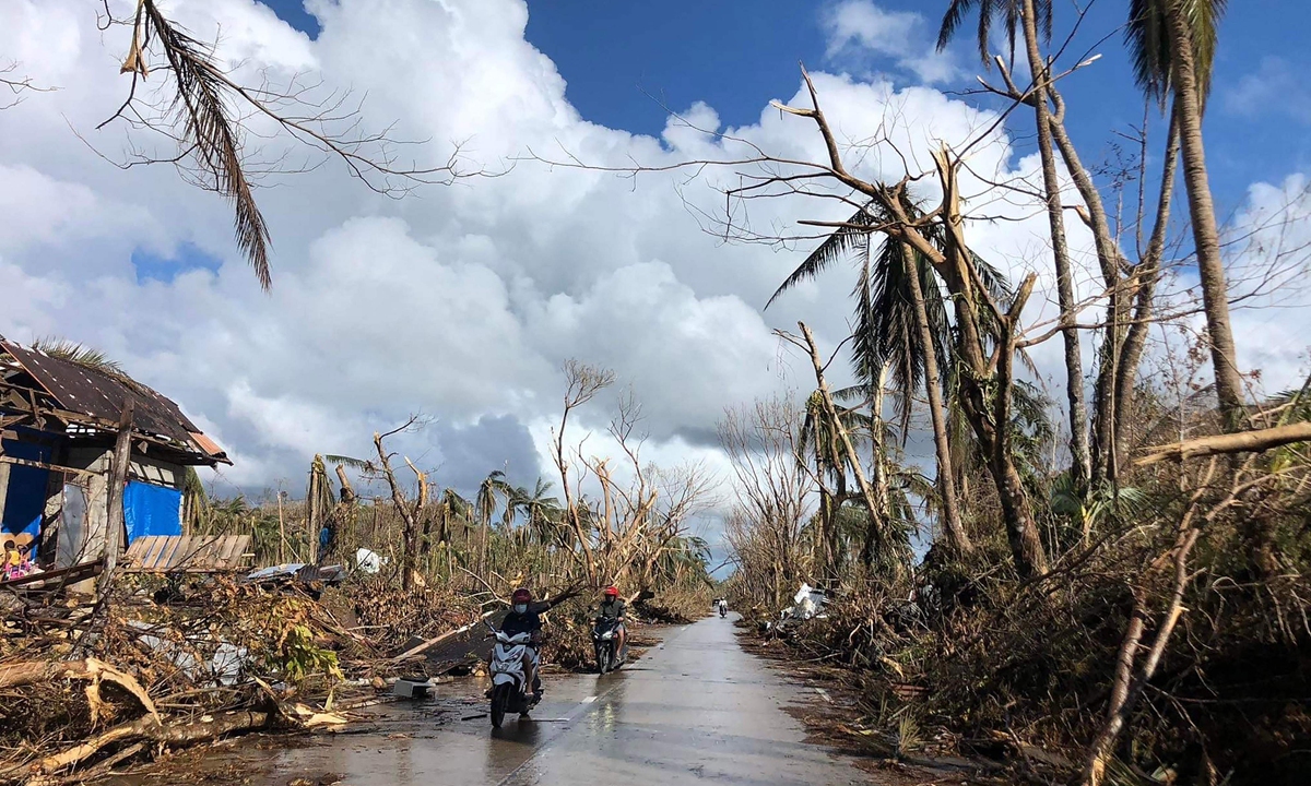 Motorists speed past fallen coconut trees at the height of Super Typhoon Rai along a highway in Del Carmen town, Siargao island, on December 20, 2021. Photo: VCG