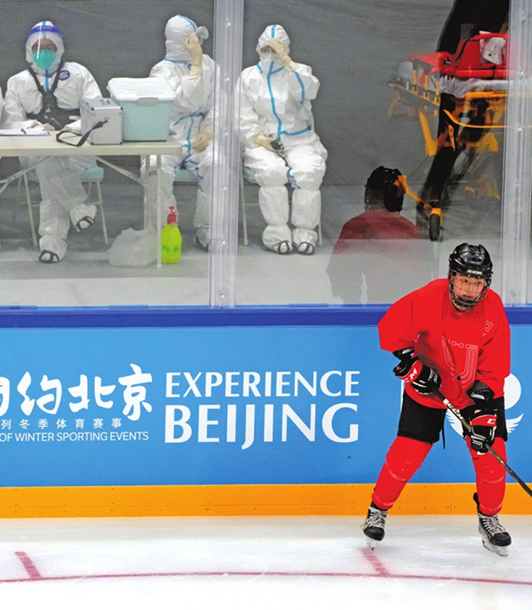 Medical personnel in protective suits watch as the China Ice Sports College hockey team practices on the ice during the Experience Beijing Ice Hockey Domestic Test Activity, a test event for the 2022 Beijing Winter Olympics, at the National Indoor Stadium in Beijing, Wednesday, November 10, 2021. Photo: VCG