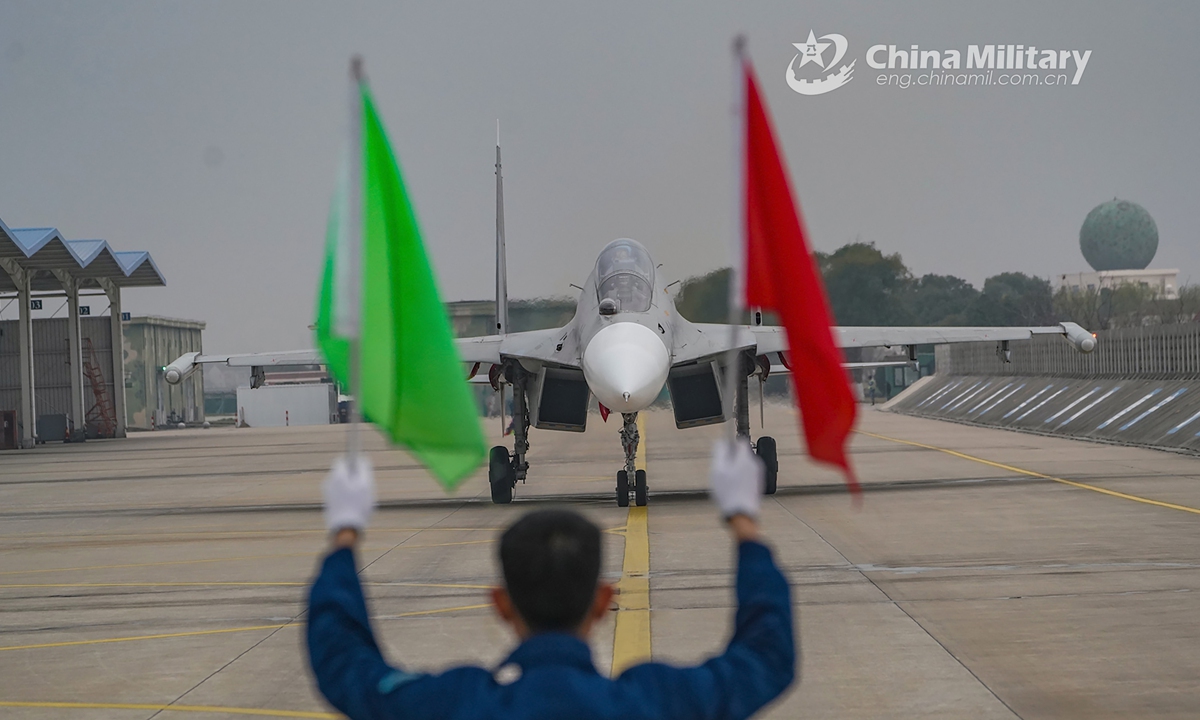 A ground crew member assigned to a naval aviation brigade under the PLA Eastern Theater Command uses flag signal to guide a fighter jet into the aircraft hangar after a flight training mission on December 16, 2021.Photo:China Military