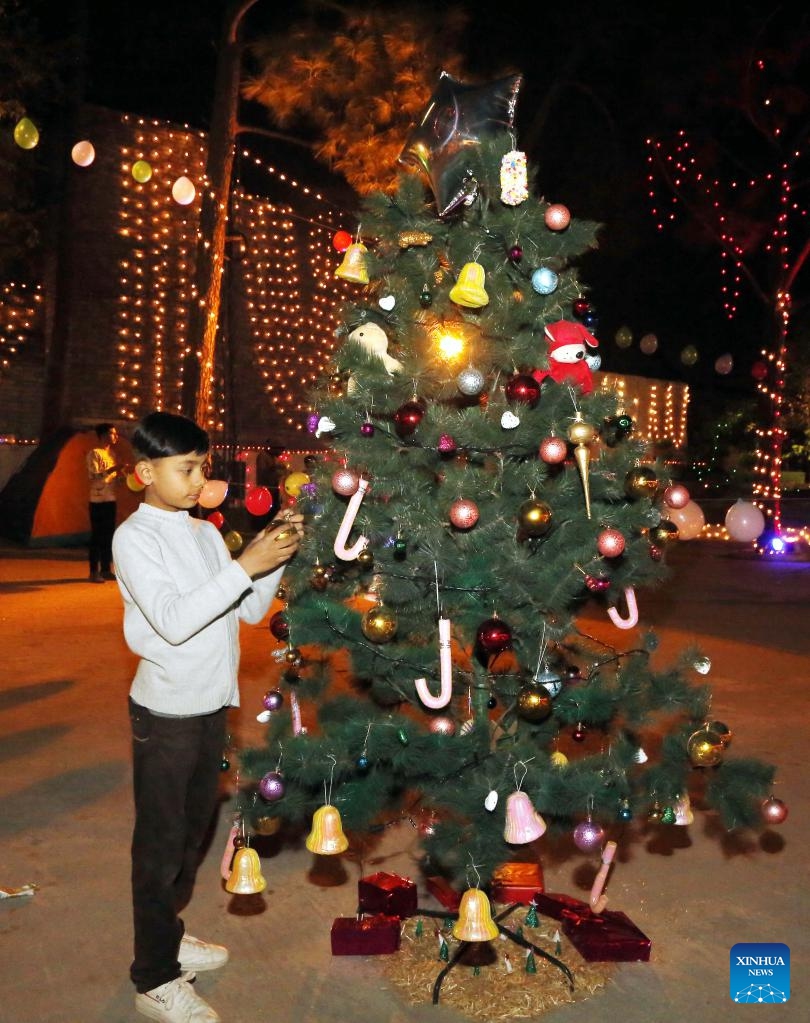 A boy decorates a Christmas tree on Christmas Eve in Islamabad, capital of Pakistan, Dec. 24, 2021. (Xinhua/Ahmad Kamal)