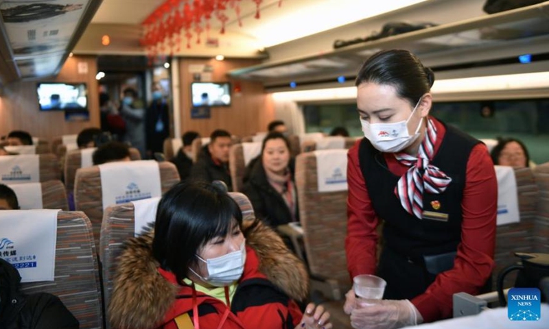 Staff members serves a passenger on a bullet train on the first operation day of the new high-speed railway line reaching the foot of the Changbai Mountains in northeast China's Jilin Province, Dec. 24, 2021. A new high-speed railway line reaching the foot of the Changbai Mountains in Jilin Province was put into operation on Dec. 24.(Photo/Xinhua)
