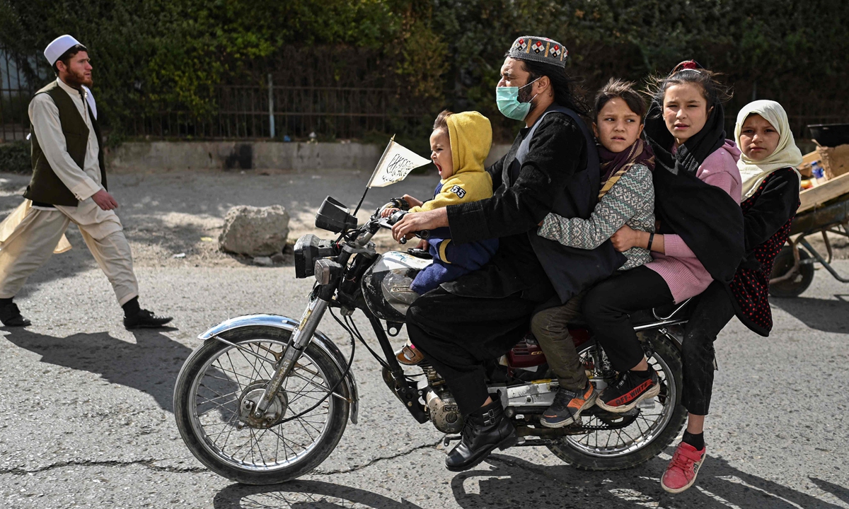 An Afghan vendor sells dried fruit on a street in a Kabul market on October 29, 2021. Right: A man rides a motorbike with a boy and three girls on a street in Kabul o