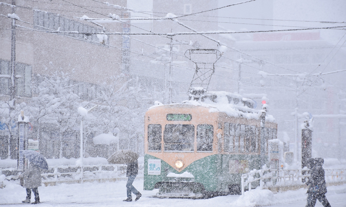 People cross a street in heavy snow in the city of Toyama, Toyama prefecture, brought by an extreme cold front along western and northern parts of the country on December 27, 2021. Photo: AFP