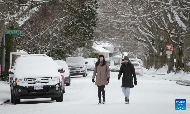People walk on a snow-covered street in Vancouver, British Columbia, Canada, on Dec. 26, 2021.Photo:Xinhua