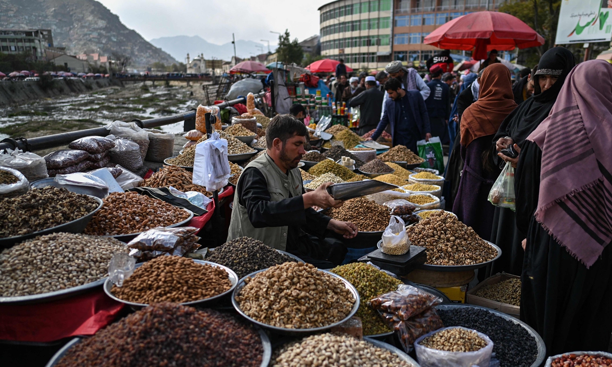 An Afghan vendor sells dry fruit along a street at a market area in Kabul on October 29, 2021. 
Right: A man rides a motorcycle with a boy and three girls along a street in Kabul o