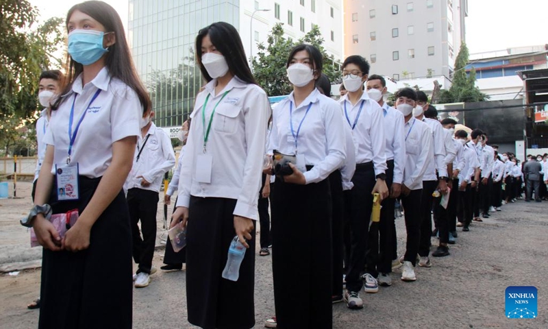 Students queue for temperature check before sitting for high school graduation exam in Phnom Penh, Cambodia on Dec. 27, 2021. A total of 114,183 Cambodian candidates took a national high school graduation exam on Monday after the COVID-19 pandemic has been brought under control(Photo: Xinhua)