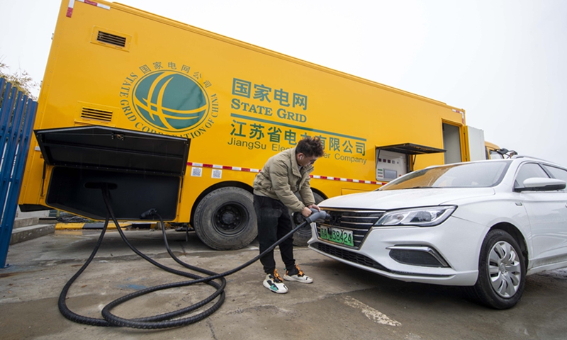 A staffer charges an electric vehicle (EV) using a mobile charging pile at the Guangling service area on the Beijing-Shanghai Expressway in Taizhou, East China's Jiangsu Province, on January 26, 2022. The mobile charging pile - a special vehicle - has four 30-kilowatt charging piles, which can serve four EVs simultaneously. It takes one hour to recharge an EV. Photo: cnsphoto

