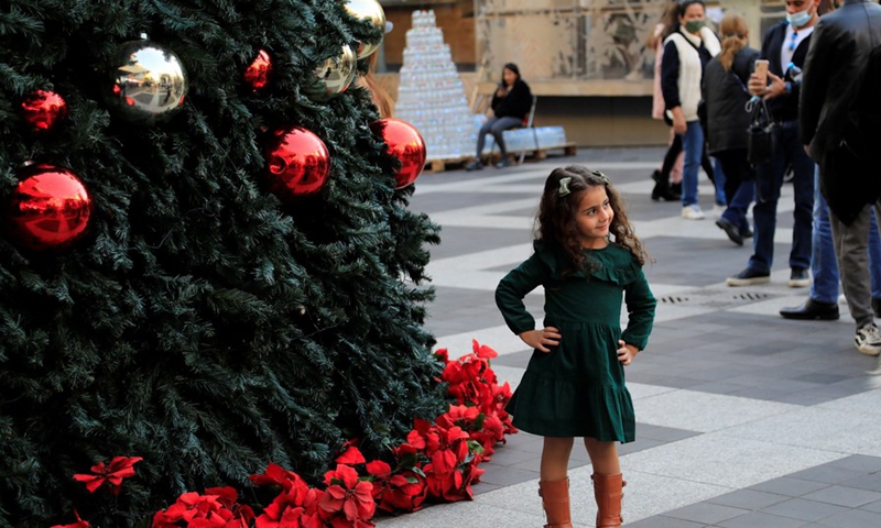 A girl poses for a photo in front of a Christmas tree in downtown Beirut, Lebanon, on Dec. 25, 2021.(Photo: Xinhua)