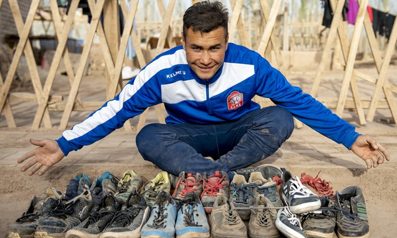 Nurmemet Sherep shows off his worn soccer shoes at his yard in Shufu County, Kashgar Prefecture, northwest China's Xinjiang Uyghur Autonomous Region, November 13, 2021 (Photo: Xinhua)