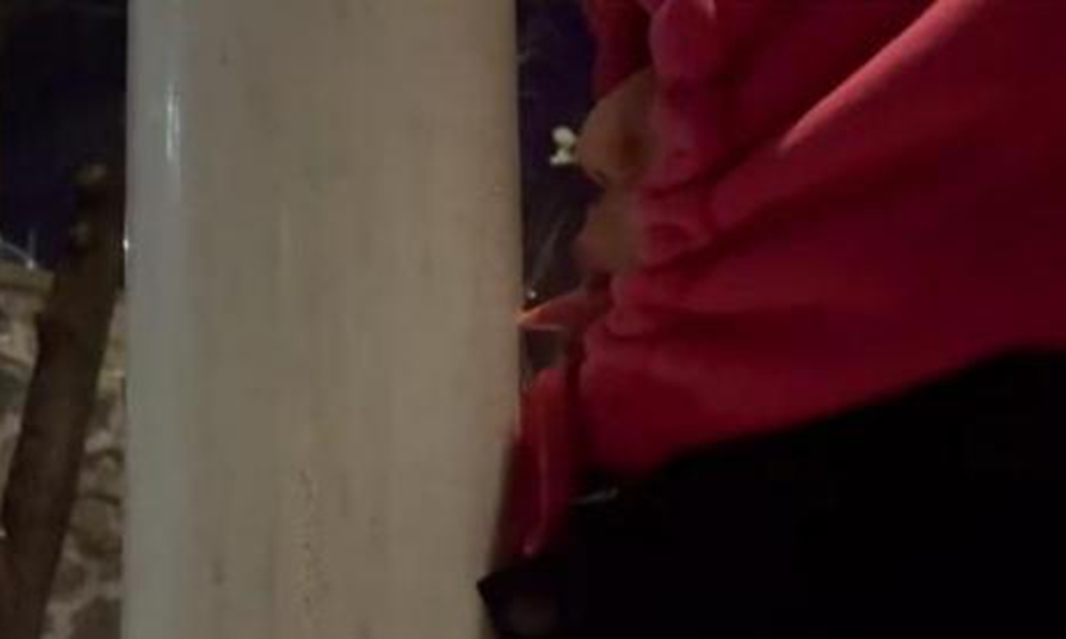 A college student's tongue is stuck firmly to a roadside fence in Changchun, Northeast China's Jilin Province. Screenshot from Weibo
