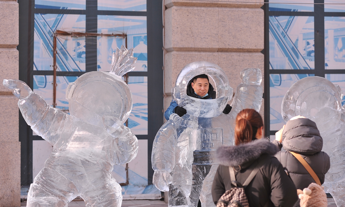 A resident in Harbin, Northeast China's Heilongjiang Province takes picture with ice sculpture of astronauts on December 28, 2021. Photo: VCG
