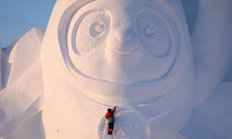 A worker finishes the main snow sculpture featuring Beijing 2022 mascots at the 34th Harbin Sun Island International Snow Sculpture Art Exposition in Harbin, northeast China's Heilongjiang Province, Dec. 27, 2021. (Xinhua/Wang Jianwei)