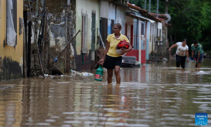 A woman wades through a flooded street after heavy rainfall in the city of Itapetinga, Bahia State, Brazil, Dec. 27, 2021.(Photo: Xinhua)