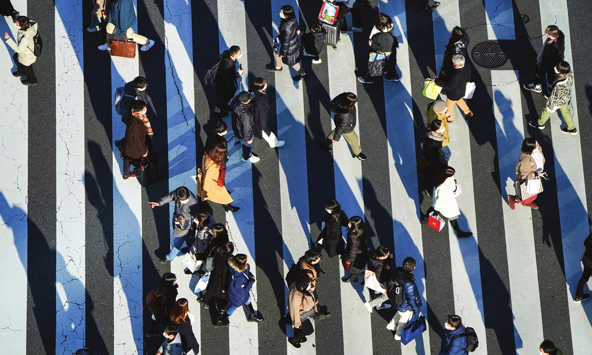 People wear face masks while walking along a pedestrian crossing on December 29, 2021, in Tokyo, Japan. Many citizens have begun heading home for the New Year  as the number of flights across the country is rebounded compared to that of 2020. Photo: VCG