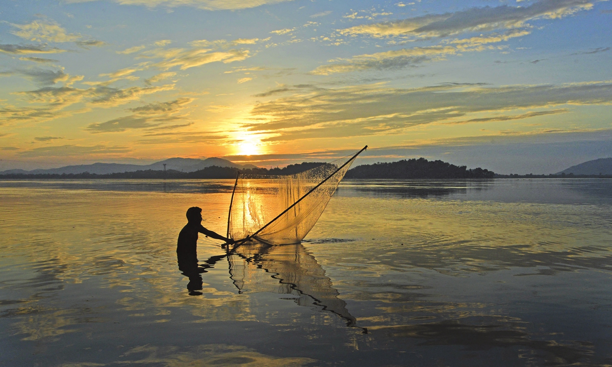 A man casts a net to fish in the Brahmaputra River at sunset in Guwahati, India on May 25, 2021.Photo: AFP