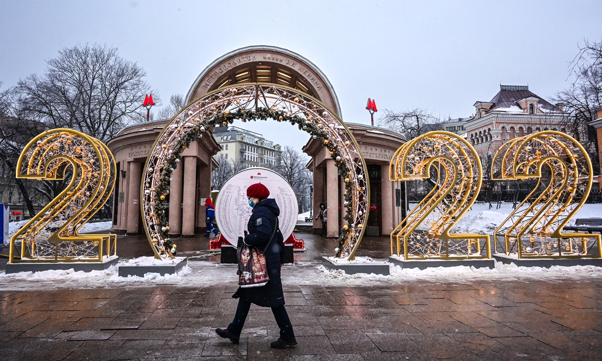A pedestrian, wearing a protective face mask, walks past New Year decorations in front of Kropotkinskaya metro station in Moscow on December 29, 2021. Every year, Moscow puts on a lavish display of decorations for the festive season, with lights, trees and installations. Photo: AFP  