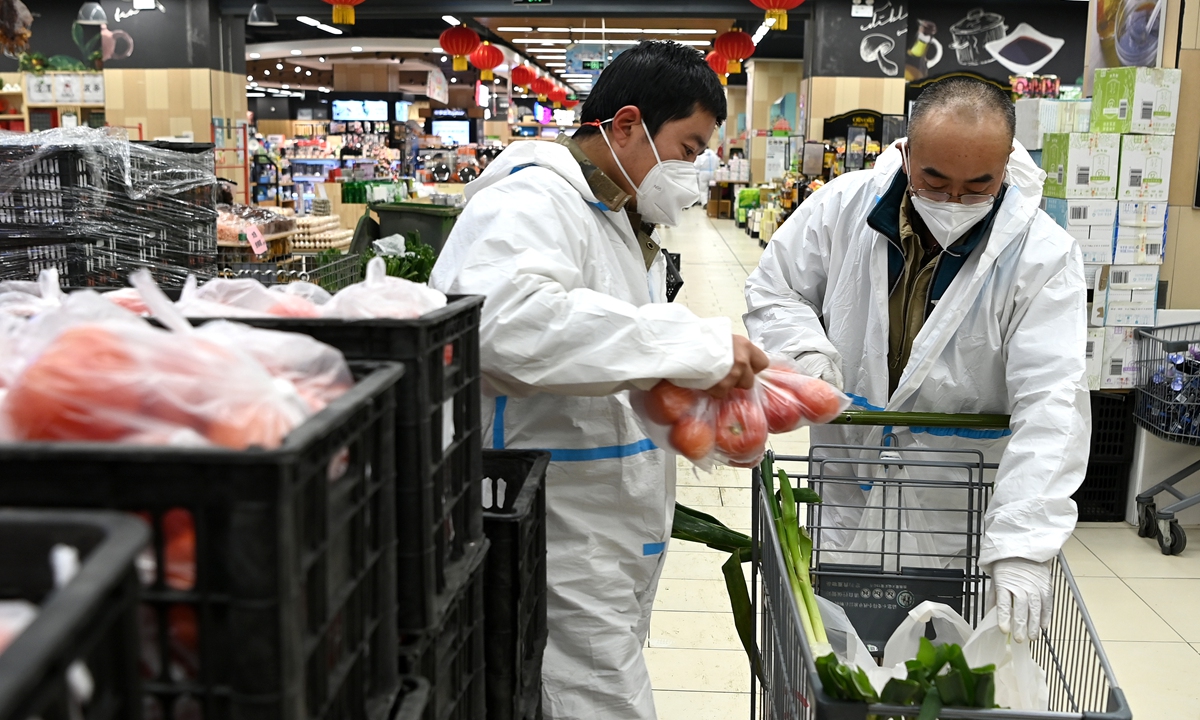 Two COVID-19 prevention workers in Xi'an, Northwest China's Shaanxi Province, buy daily necessities in a supermarket on December 29, 2021. Xi'an strengthened its COVID-19 prevention measures on December 27, requiring residents to avoid going out. The government has dispatched personnel to buy living necessities for residents. Photo: Xinhua
