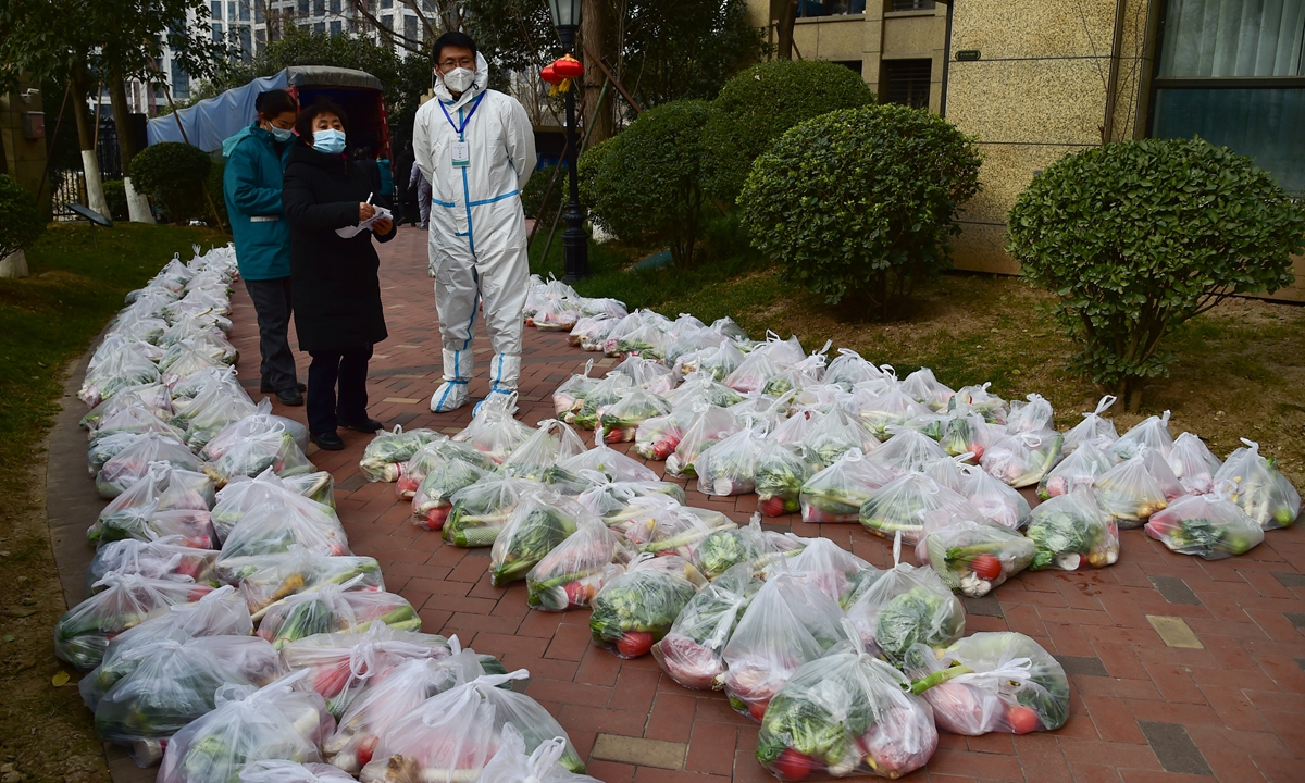 Volunteers and COVID-19 prevention workers distribute daily necessities to residents in a sealed off residential compound in Xi'an, Northwest China's Shaanxi Province on December 30. Photo: VCG
