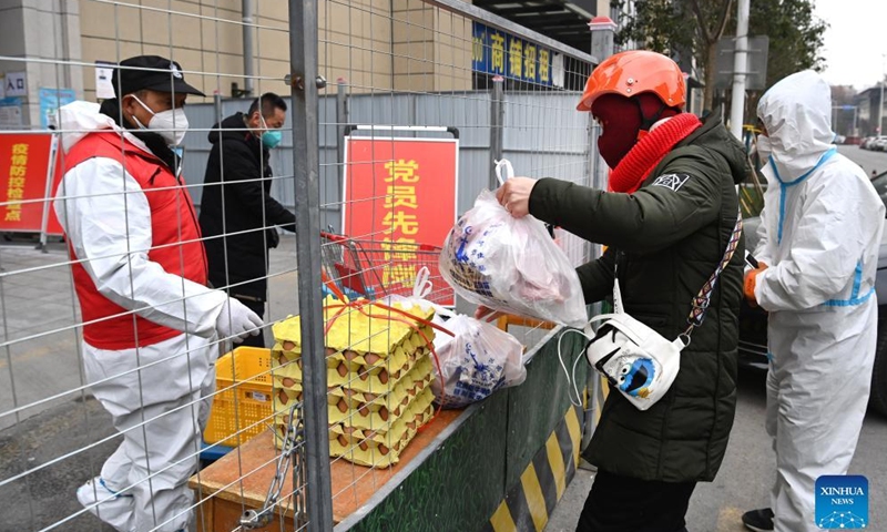 A deliveryman carries daily necessities at a residential area under closed-off management in Xi'an, northwest China's Shaanxi Province, Dec. 31, 2021. Xi'an imposed closed-off management for communities and villages on Dec. 23 in an effort to curb the spread of the latest COVID-19 resurgence. (Xinhua/Tao Ming)
