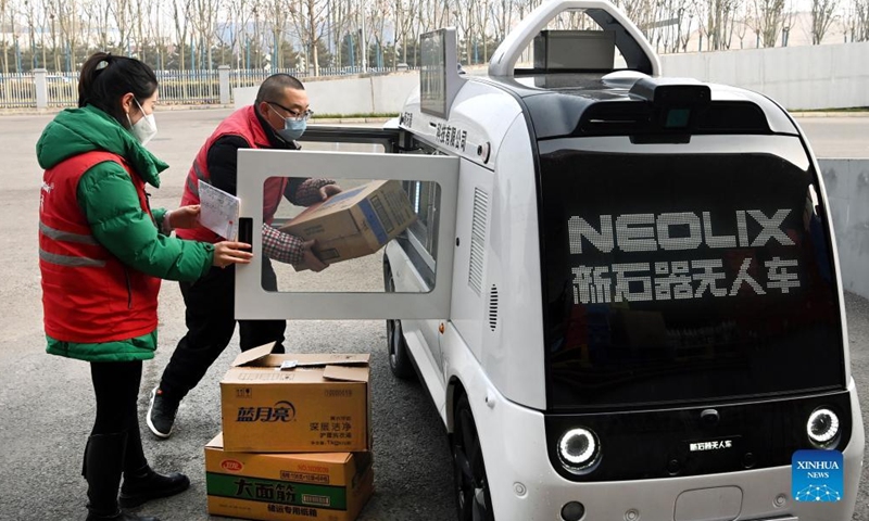 A staff member loads up an unmanned delivery vehicle with goods in Xi'an, capital of northwest China's Shaanxi Province, Jan. 9, 2022. The driverless vehicle is designed to transport goods with a maximum weight of 320 kg per trip. It can traverse 6.5 km through the lanes on roads on a single trip. (Xinhua/Tao Ming)