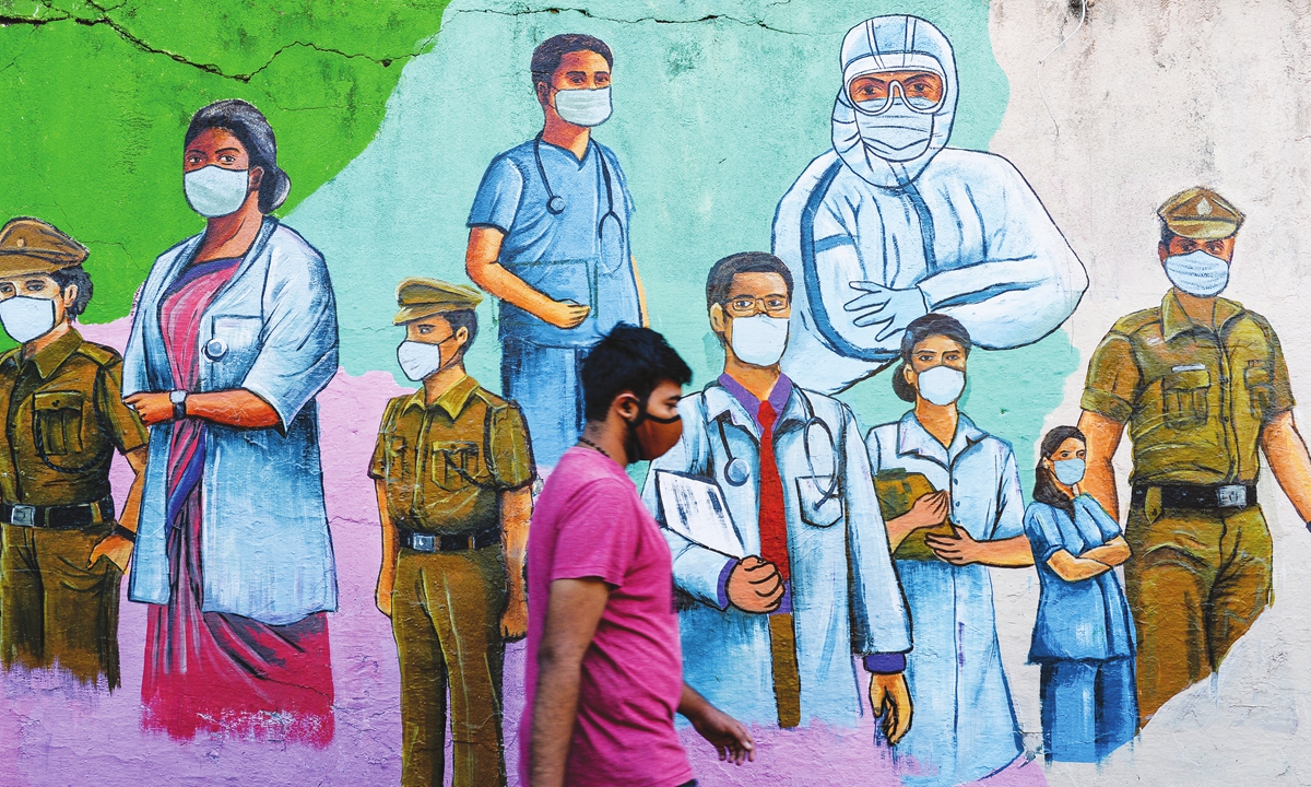 A pedestrian walks past a wall mural featuring illustrations of frontline workers urging citizens to wear masks properly in order to raise awareness about COVID-19 safety protocols in Mumbai, India on January 9, 2022.  India reported 159,632 new COVID-19 cases on Sunday. Photo: AFP