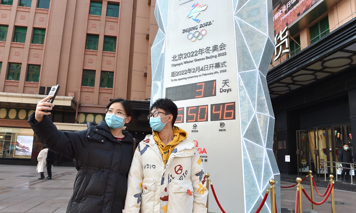 People take a selfie in front of a countdown board for the Beijing 2022 Olympic and Paralympic Winter Games in front of a department store on Wangfujing Street, Beijing on January 4, 2022, just 31 days before the opening of the Winter Games. Photo: VCG