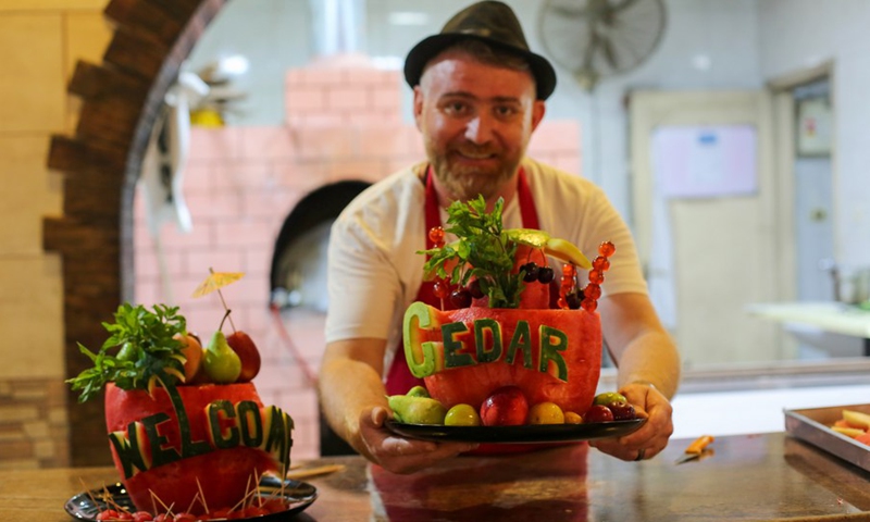 Chef Wareef Qassem, 40, displays watermelons engraved with the word Welcome, and the name of his watermelon restaurant as a way to attract customers, in Gaza City, July 9, 2020 (Photo: Xinhua)