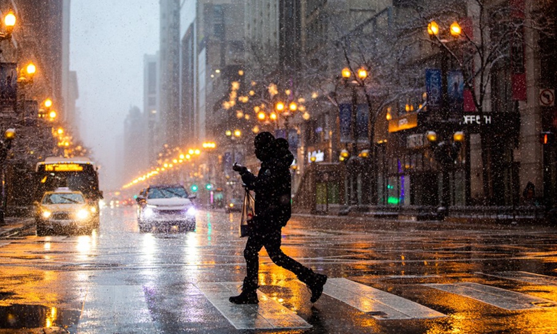 A man crosses State Street in downtown Chicago, the United States, on Jan. 1, 2022. A winter storm hit Chicago on Saturday, with snow accumulation expected to reach 10 to 18 centimeters.(Photo: Xinhua)