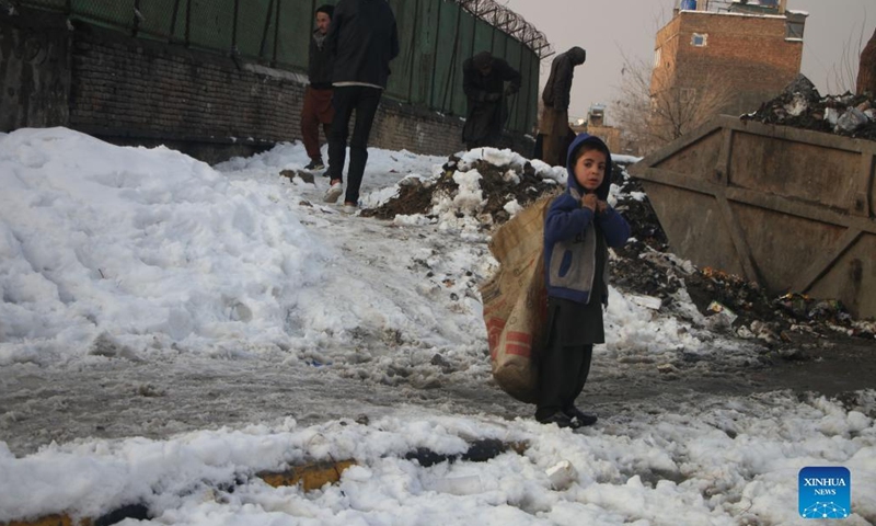 Children collect garbage in Kabul, Afghanistan, Jan. 5, 2022. Heavy snow started falling across the country on Monday, bringing new hardships to needy families who have little food to eat and no way to heat their makeshift shelters. Many with no choice but to scavenge on the streets of Kabul.(Photo: Xinhua)