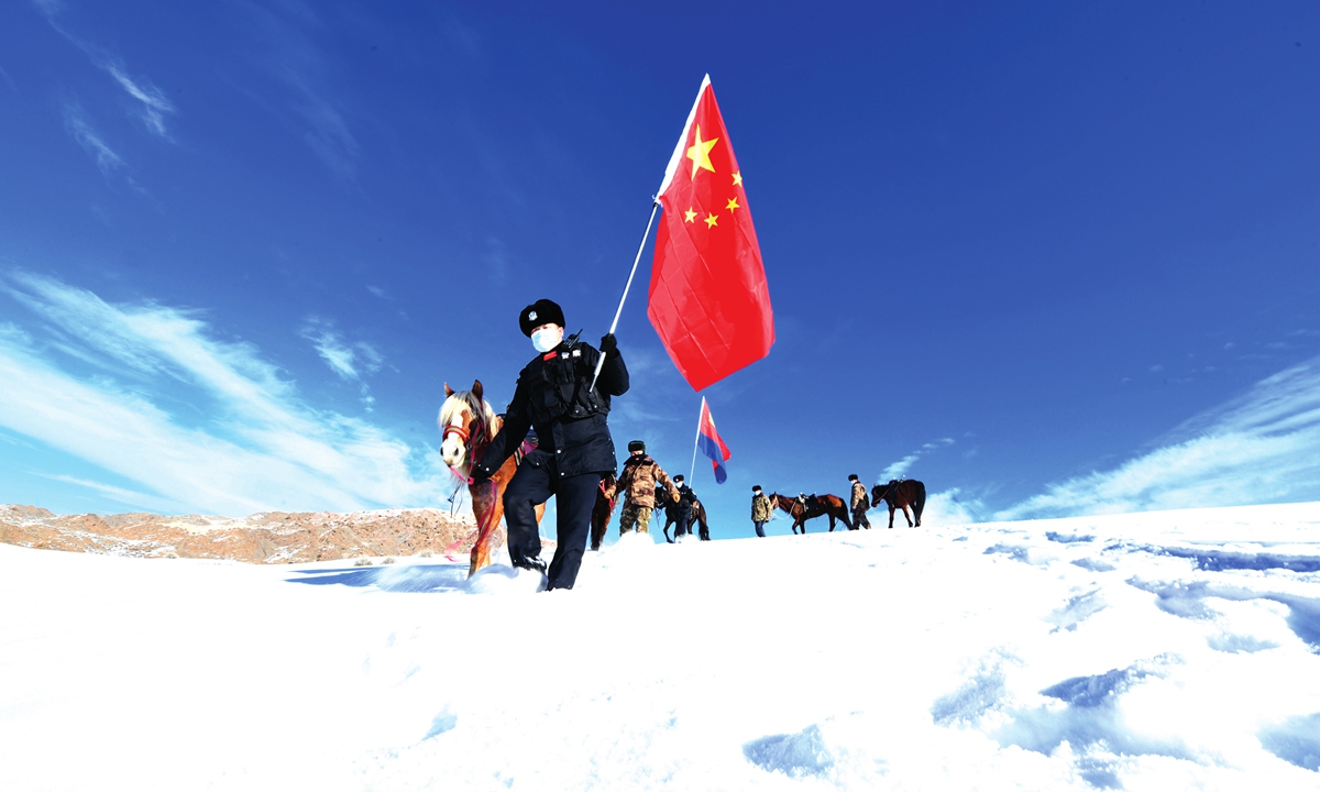 Border police officers in Xinjiang patrol while holding the national flag and the flag of the police on January 8, 2022 to welcome the Chinese People's Police Day. Photos: IC
