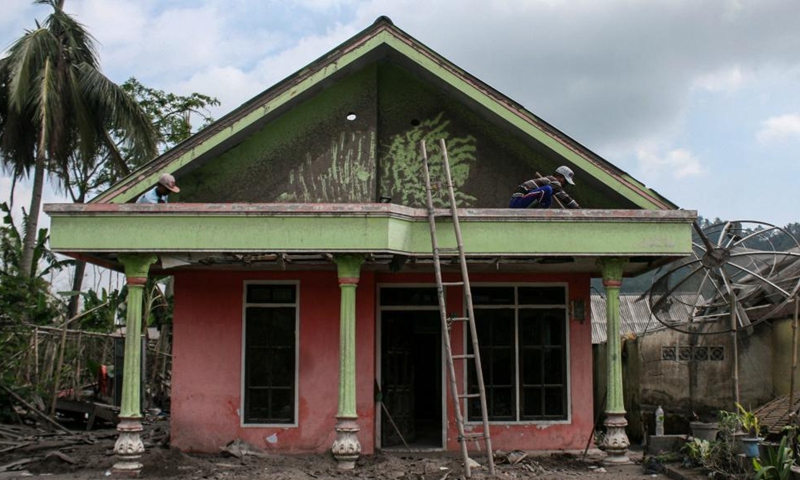 People clean volcanic ash spewed from Mount Semeru on the roof of a house at Curah Kobokan village in Lumajang, East Java, Indonesia, Jan. 9, 2022.Photo:Xinhua