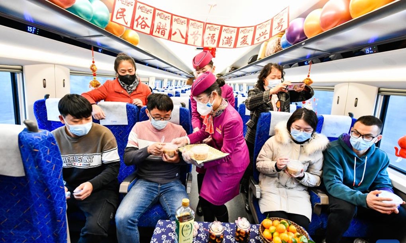 Crew members serve free Laba porridge to passengers in the bullet train C5980 from Guiyang in southwest China's Guizhou Province to Chengdu in southwest China's Sichuan Province, Jan. 9, 2022. Crew members of the train C5980 held various activities to greet the Laba Festival.(Photo: Xinhua)