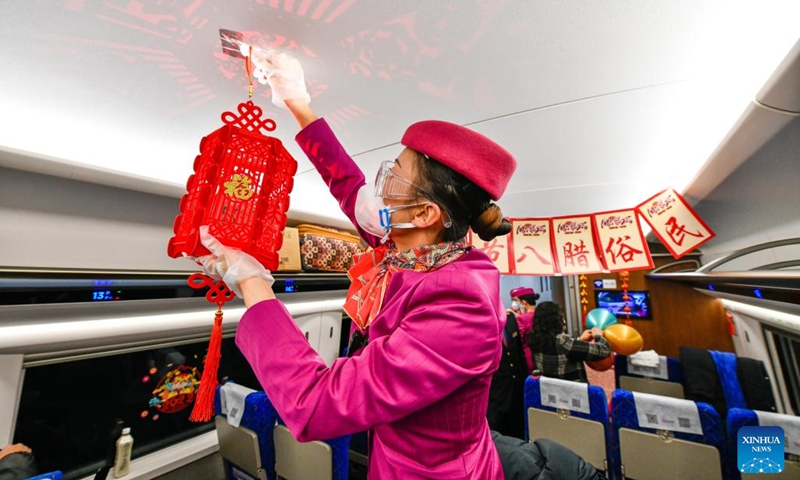 A crew member hangs a lantern in the bullet train C5980 from Guiyang in southwest China's Guizhou Province to Chengdu in southwest China's Sichuan Province, Jan. 9, 2022. Crew members of the train C5980 held various activities to greet the Laba Festival.(Photo: Xinhua)