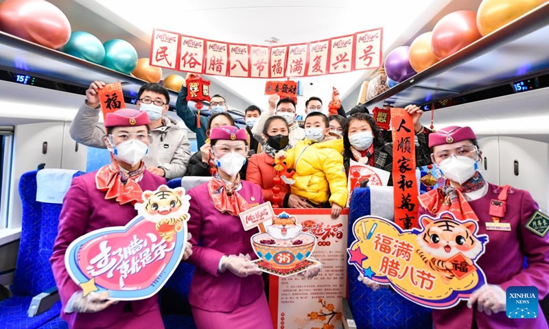 People pose for a photo in the bullet train C5980 from Guiyang in southwest China's Guizhou Province to Chengdu in southwest China's Sichuan Province, Jan. 9, 2022. Crew members of the train C5980 held various activities to greet the Laba Festival.(Photo: Xinhua)