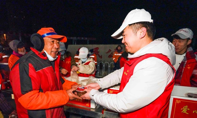 A volunteer serves free Laba porridge to sanitation workers in Zunhua, north China's Hebei Province, Jan. 10, 2022. The Laba Festival, literally the eighth day of the 12th lunar month, is considered a prelude to the Spring Festival, or Chinese Lunar New Year. It is customary to eat Laba porridge on this day.(Photo: Xinhua)