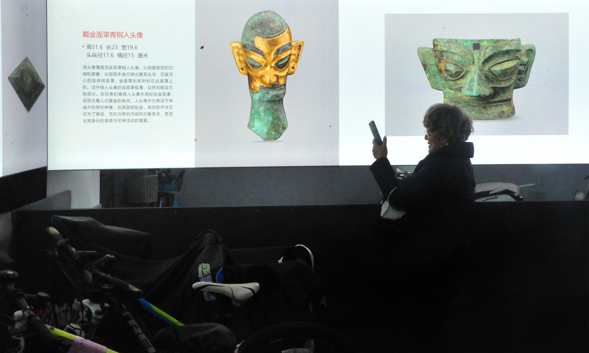 Residents on Sunday take pictures of an exhibition of Longmen Grottoes and Sanxingdui cultural relics held in a parking garage of a residential community in Shanghai. Photo: IC