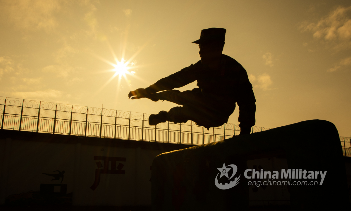 A soldier assigned to the Beihai detachment under the People's Armed Police Force (PAP) Guangxi Corps leaps over a kneeboard barrier in a fitness training course on Dec. 21, 2021. (eng.chinamil.com.cn/Photo by Yu Haiyang)