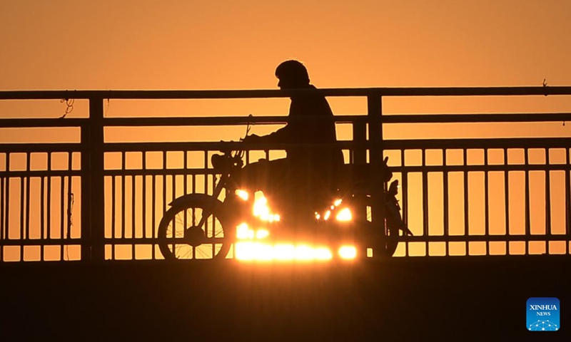 Photo taken on Jan. 11, 2022 shows the silhouette of a man riding a motorbike on a bridge during sunset in Islamabad, capital of Pakistan.(Photo: Xinhua)