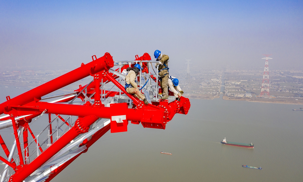 Workers of Jiangsu Power Transmission and Transformation Co erect an iron tower at a high altitude. This completes the construction of the transmission tower for the 500-kilovolt project spanning the Yangtze River from Fengcheng to Meili in Wuxi, East China's Jiangsu Province, setting a record for the height of the world's largest transmission tower. 
Photo: cnsphoto