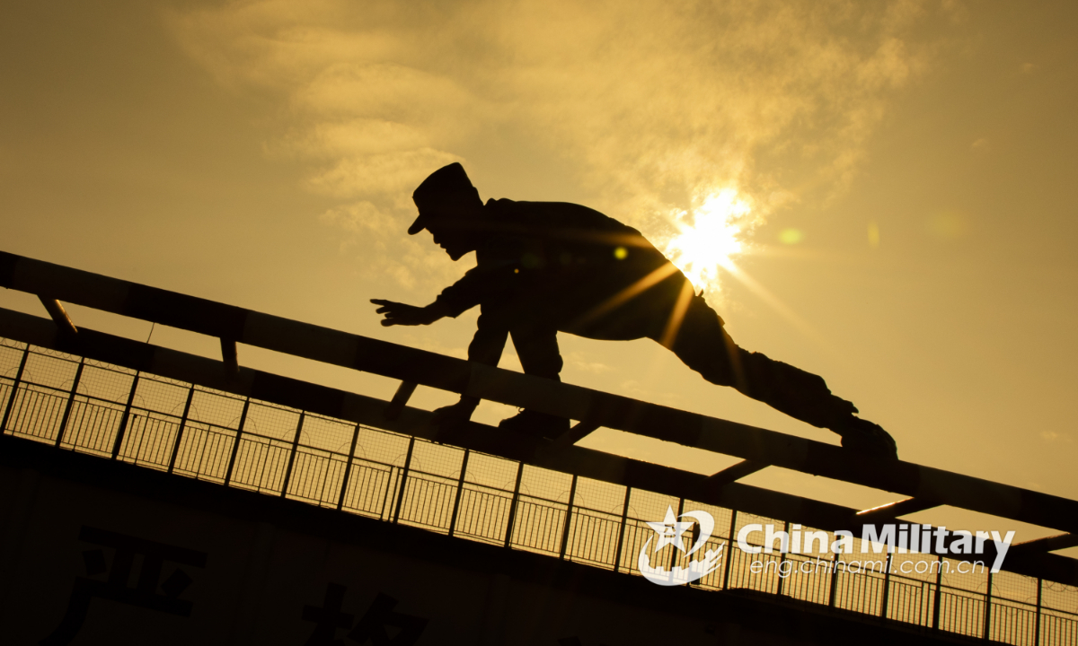 A soldier climbs over a scaling ladder in a fitness training course conducted by the detachment under the People's Armed Police Force (PAP) Beihai Corps on Dec.21, 2021. (eng.chinamil.com.cn/Photo by Yu Haiyang)
