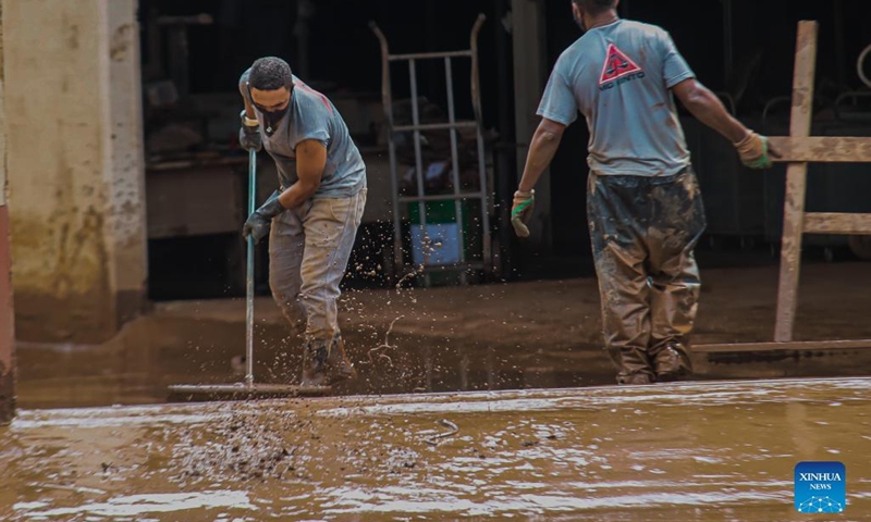Workers clean a street after a flood caused by heavy rains in Sabara, Minas Gerais state, Brazil, on Jan. 11, 2022. At least 10 people were killed in the past 24 hours after heavy rains in the southeastern Brazilian state of Minas Gerais, and more than 13,000 people were forced to leave their homes, the regional civil defense authorities said Tuesday.(Photo: Xinhua)