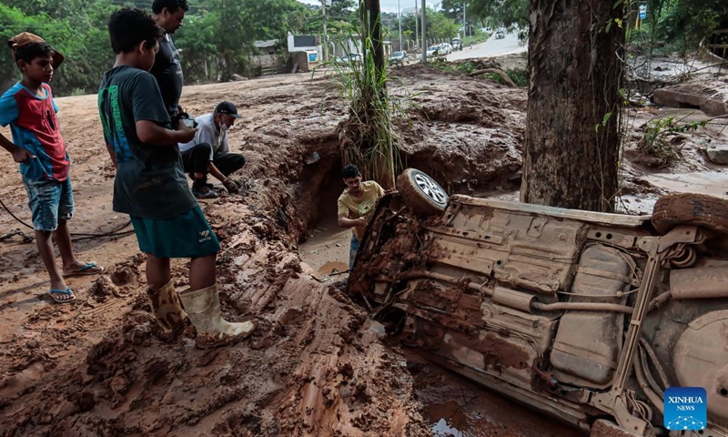 People try to pull a vehicle out of a pothole after a flood caused by heavy rains in Sabara, Minas Gerais state, Brazil, on Jan. 11, 2022. At least 10 people were killed in the past 24 hours after heavy rains in the southeastern Brazilian state of Minas Gerais, and more than 13,000 people were forced to leave their homes, the regional civil defense authorities said Tuesday.(Photo: Xinhua)