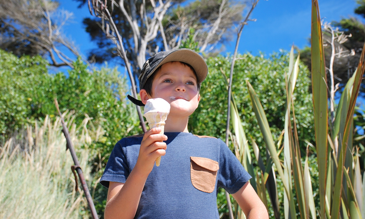 A boy eats ice cream on a beach. Photo: VCG
