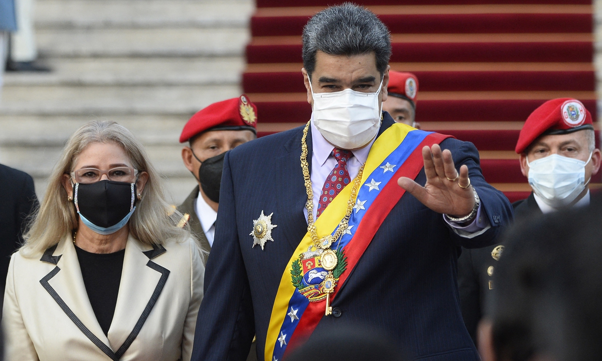 Venezuelan President Nicolas Maduro (middle), accompanied by his wife Cilia Flores (left), arrives to the Federal Legislative Palace to deliver his annual report to the National Assembly in Caracas, on January 15, 2022. Maduro says he expects Venezuelan economy grew 4 percent in 2021, signaling an 