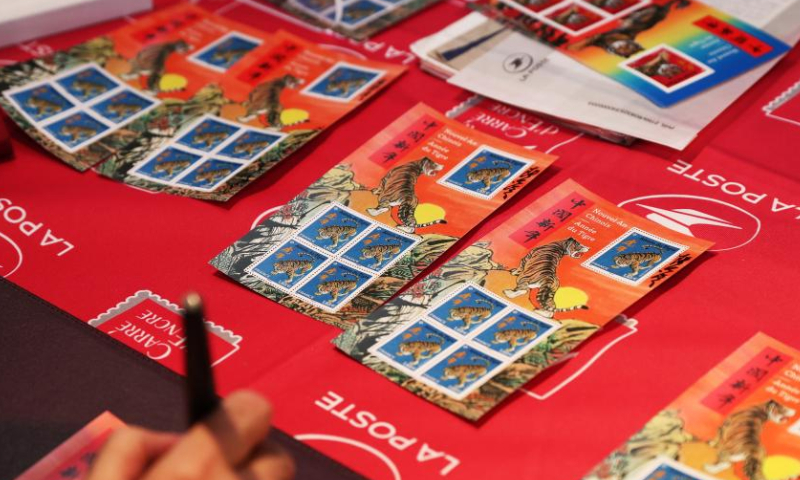 Paris-based Chinese artist Chen Jianghong signs on the Year of Tiger commemorative stamps designed by him during an issuing ceremony in Paris, France, Jan. 22, 2022. French postal service company La Poste issued two Year of Tiger stamps in a ceremony here on Saturday to celebrate the Chinese Lunar New Year. This year's stamps are designed by Paris-based Chinese artist Chen Jianghong. (Xinhua)