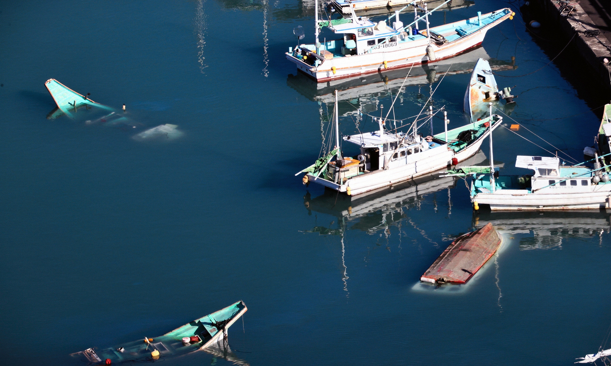 In this aerial image, some fishing boats are sunk and overturned in Muroto, Kochi, Japan on January 16, 2022 after the tsunami triggered by a massive volcanic eruption in Tonga. No casualties were reported in Japan. Photo: VCG