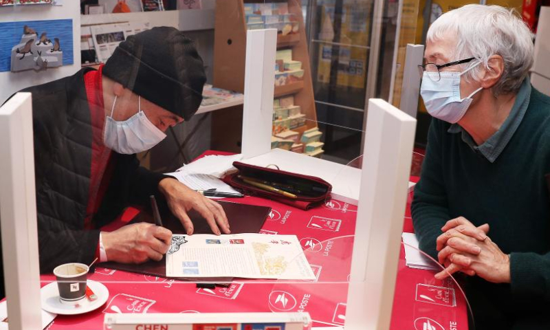 Paris-based Chinese artist Chen Jianghong (L) signs on the Year of Tiger commemorative stamps designed by him during an issuing ceremony in Paris, France, Jan. 22, 2022. French postal service company La Poste issued two Year of Tiger stamps in a ceremony here on Saturday to celebrate the Chinese Lunar New Year. This year's stamps are designed by Paris-based Chinese artist Chen Jianghong. (Xinhua)