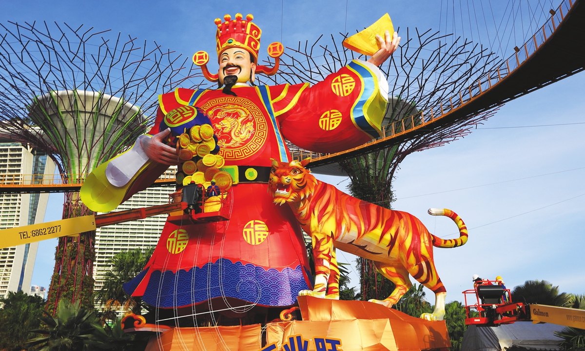 Workers put up gold coins on a giant lantern display featuring the God of Fortune next to a tiger on January 16, 2022 in Singapore as it prepares to celebrate Chinese New Year. There were around 2.96 million Chinese-Singaporeans in the country as of June 2021. Photo: VCG