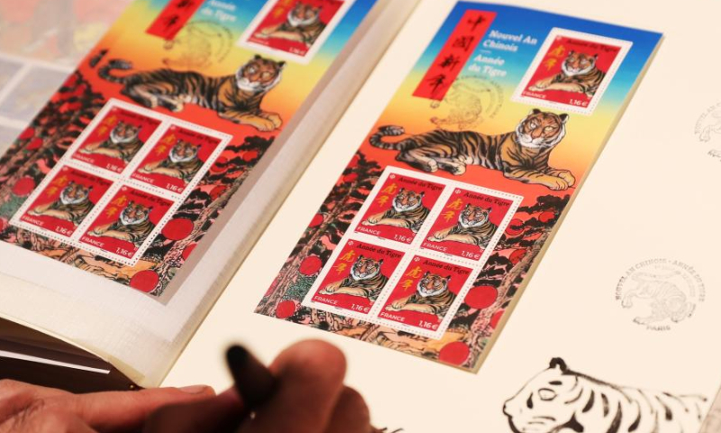 Paris-based Chinese artist Chen Jianghong signs on the Year of Tiger commemorative stamps designed by him during an issuing ceremony in Paris, France, Jan. 22, 2022. French postal service company La Poste issued two Year of Tiger stamps in a ceremony here on Saturday to celebrate the Chinese Lunar New Year. This year's stamps are designed by Paris-based Chinese artist Chen Jianghong. (Xinhua)