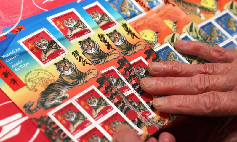 A customer displays the Year of Tiger commemorative stamps purchased during an issuing ceremony in Paris, France, Jan. 22, 2022. French postal service company La Poste issued two Year of Tiger stamps in a ceremony here on Saturday to celebrate the Chinese Lunar New Year. This year's stamps are designed by Paris-based Chinese artist Chen Jianghong. (Xinhua)